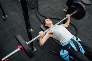 Mann som tar benkpress og ligger på treningsbenk